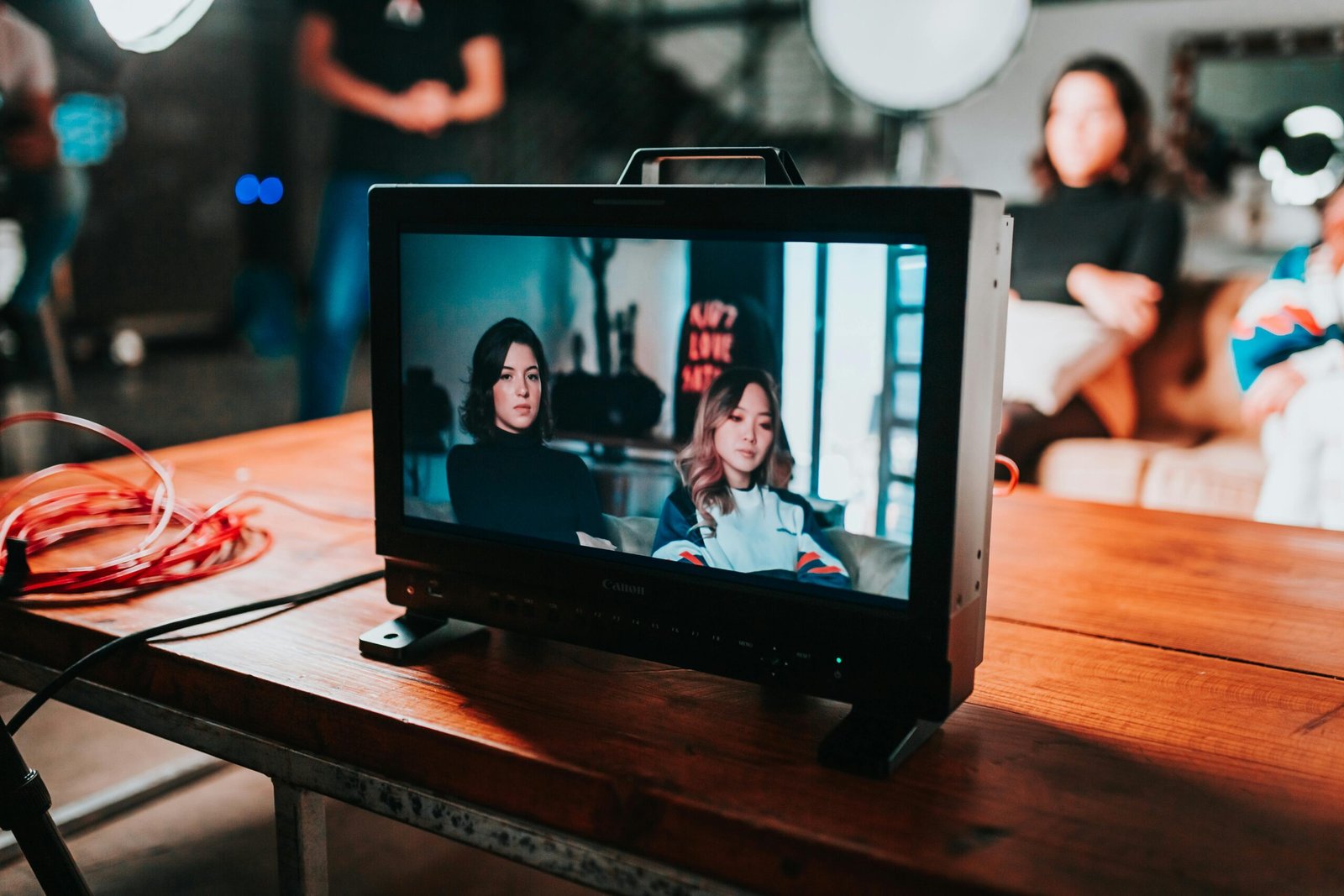 A professional photoshoot setup displaying two women on a monitor in a studio environment.
